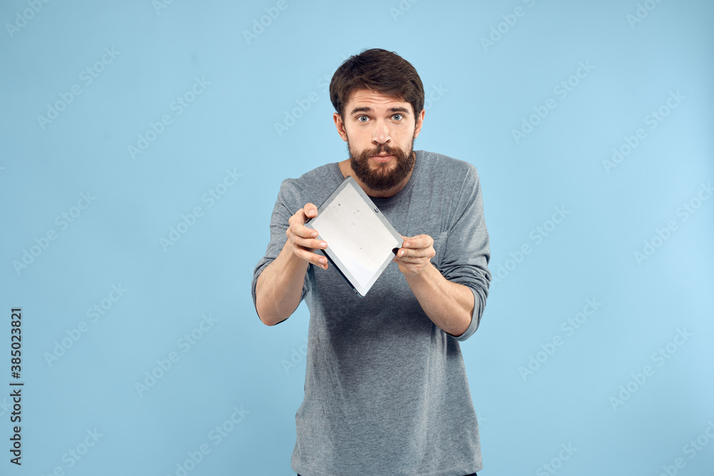 Emotional man with a tablet in the hands of a wireless device internet technology lifestyle blue background Emotional man with a tablet in the hands of a wireless device internet technology lifestyle blue background