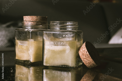 Photos two aromatic ascent candles in a glass square port with cork lead on a glass rustic table top