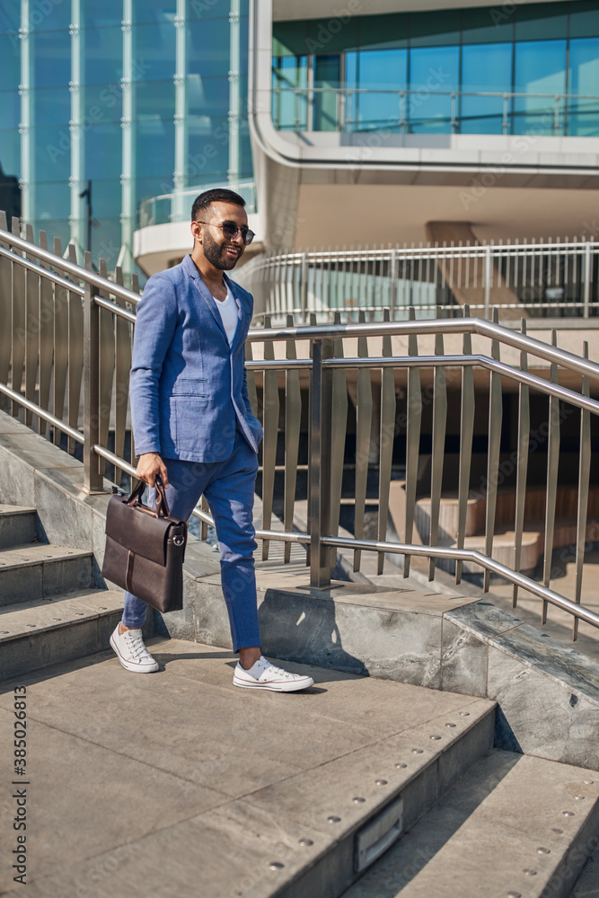 Smiling trendy Indian arabic business man walking in modern city