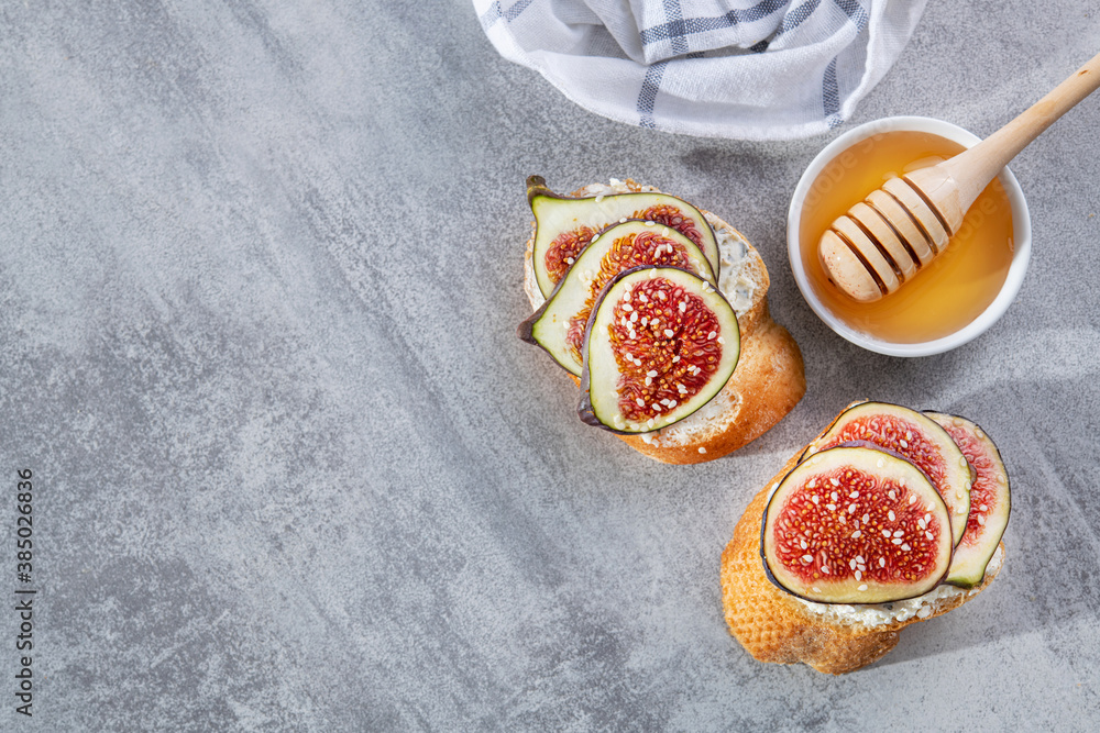 Crispy bun with cream cheese and fresh slice figs, sesame seeds and a bowl of honey Crispy bun with cream cheese and fresh slice figs, sesame seeds and a bowl of honey