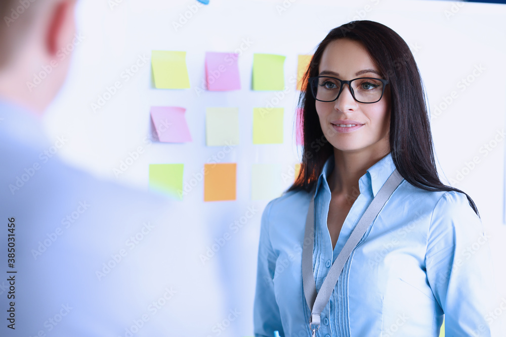 Φωτογραφία Businesswoman in glasses stands next to white board opposite colleague