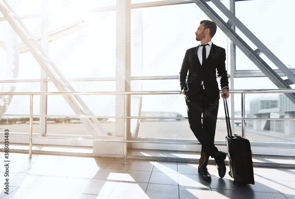 Successful businessman standing next to window at airport Successful businessman standing next to window at airport