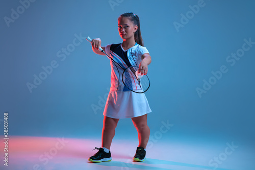Leader. Beautiful dwarf woman practicing in badminton isolated on blue background in neon light. Lifestyle of inclusive people, diversity and equility. Sport, activity and movement. Copyspace for ad. photo