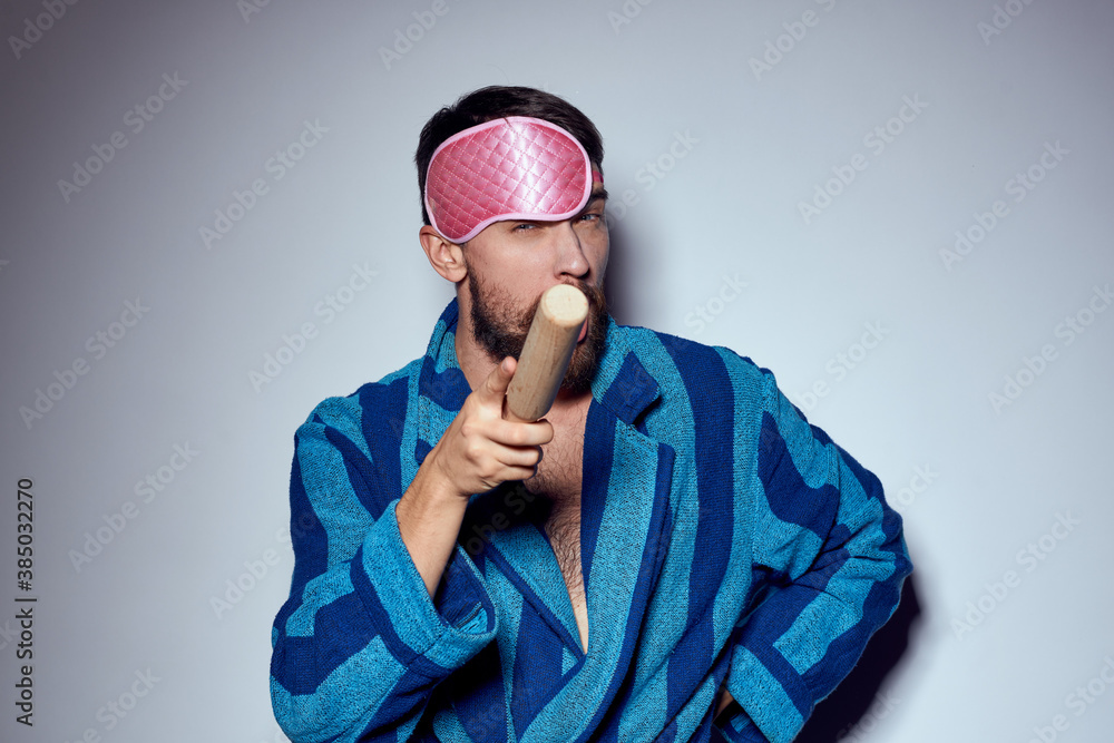 a man in a pink sleep mask holds a rolling pin in his hands and emotions energy aggression model blue robe a man in a pink sleep mask holds a rolling pin in his hands and emotions energy aggression model blue robe