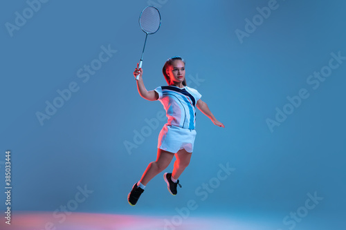 Action. Beautiful dwarf woman practicing in badminton isolated on blue background in neon light. Lifestyle of inclusive people, diversity and equility. Sport, activity and movement. Copyspace for ad.