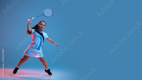 Motion. Beautiful dwarf woman practicing in badminton isolated on blue background in neon light. Lifestyle of inclusive people, diversity and equility. Sport, activity and movement. Copyspace, flyer