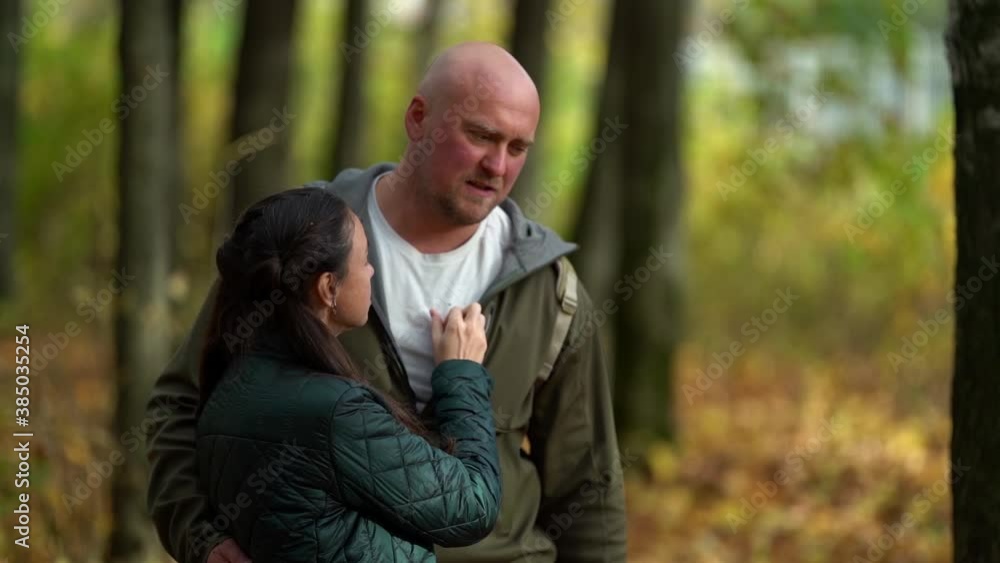 Happy adult married couple hugging and talking in the woods. A bald tall man walks with his woman Happy adult married couple hugging and talking in the woods. A bald tall man walks with his woman