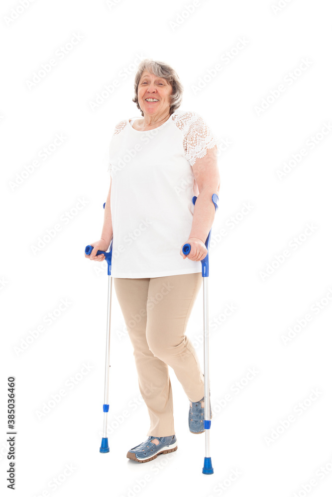 Seniorin steht auf Gehhilfen und lächelt in die Kamera vor weißem Hintergrund Seniorin steht auf Gehhilfen und lächelt in die Kamera vor weißem Hintergrund