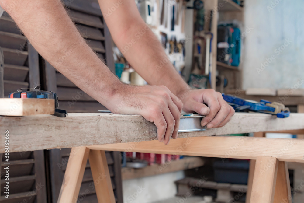 Male carpenter working with wood material in a garage. Male carpenter working with wood material in a garage.