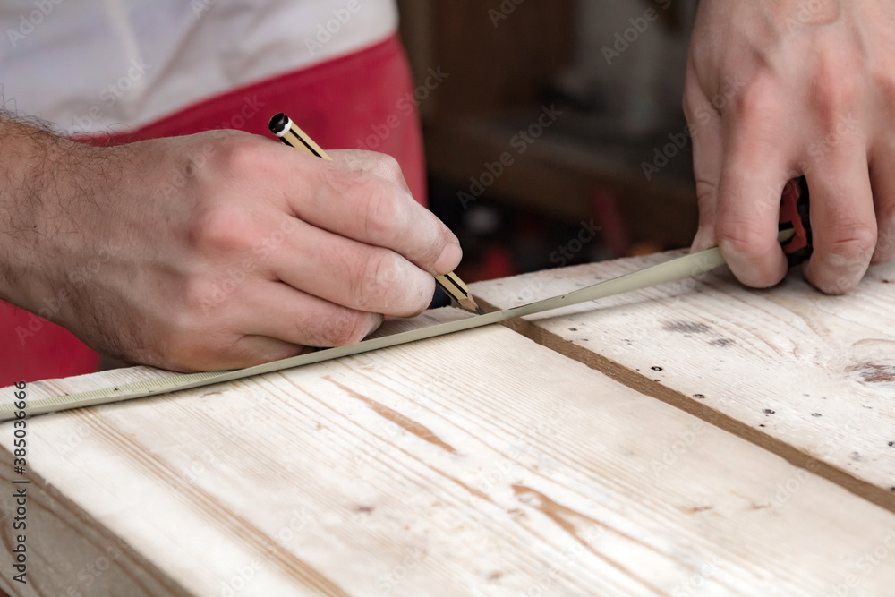 Male carpenter working with wood material in a garage. Male carpenter working with wood material in a garage.