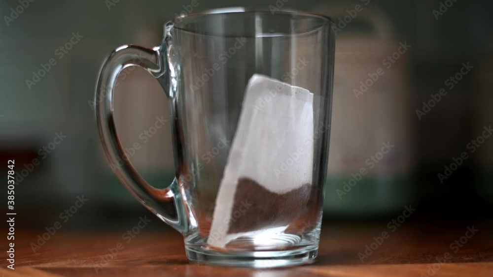 Water poured into glass cup with tea bag creating a coloufull cup. shallow depth of field focusing on cup Water poured into glass cup with tea bag creating a coloufull cup. shallow depth of field focusing on cup