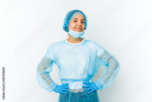 Young surgeon latin woman isolated on white background confident keeping hands on hips. © Asier