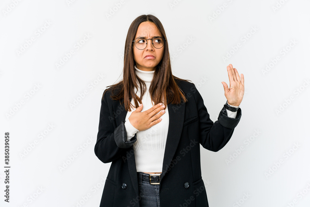 Young mixed race business woman isolated on white background taking an oath, putting hand on chest. Young mixed race business woman isolated on white background taking an oath, putting hand on chest.
