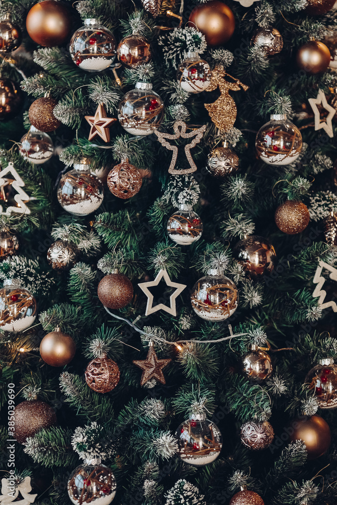 Close-up background of green fluffy Christmas tree with various decorations in shape of angels, Christmas balls, stars and garland.