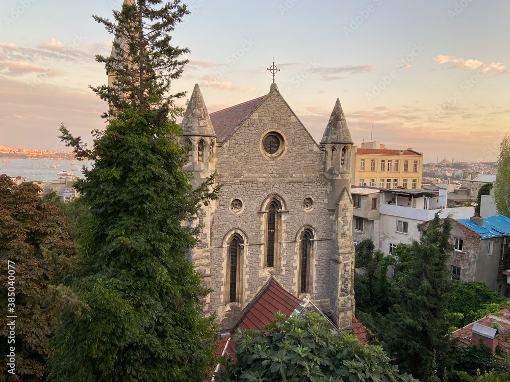 Old vintage medievel stone church building surrounded with trees. İstanbul Bosphorus at the background and ships