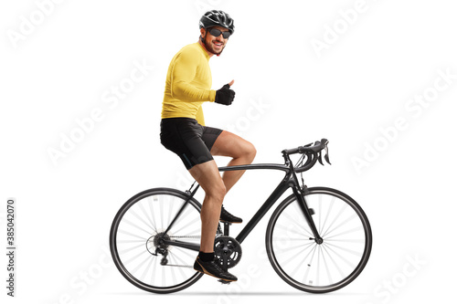 Male cyclist with a helmet riding a road bicycle and showing thumbs up