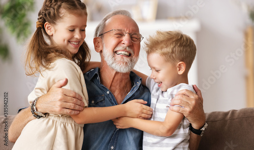 Grandfather hugging grandchildren on sofa. photo