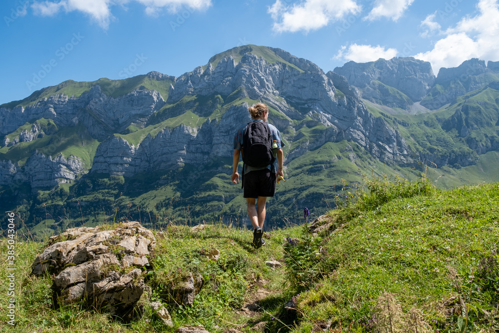 Junger Mann mit Rucksack blickt auf Berggipfel Panorama in Appenzell, Schweiz