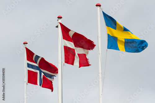 Three scandidavian flags in the wind against the sky