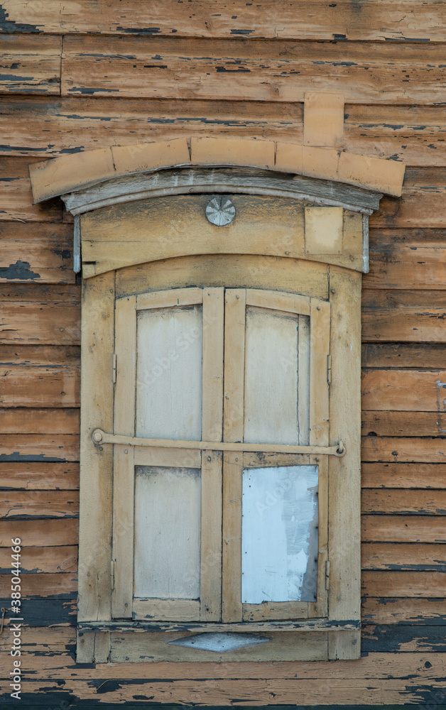 old wooden window with closed shutters on the wall with scuffed paint. ancient, wooden architecture