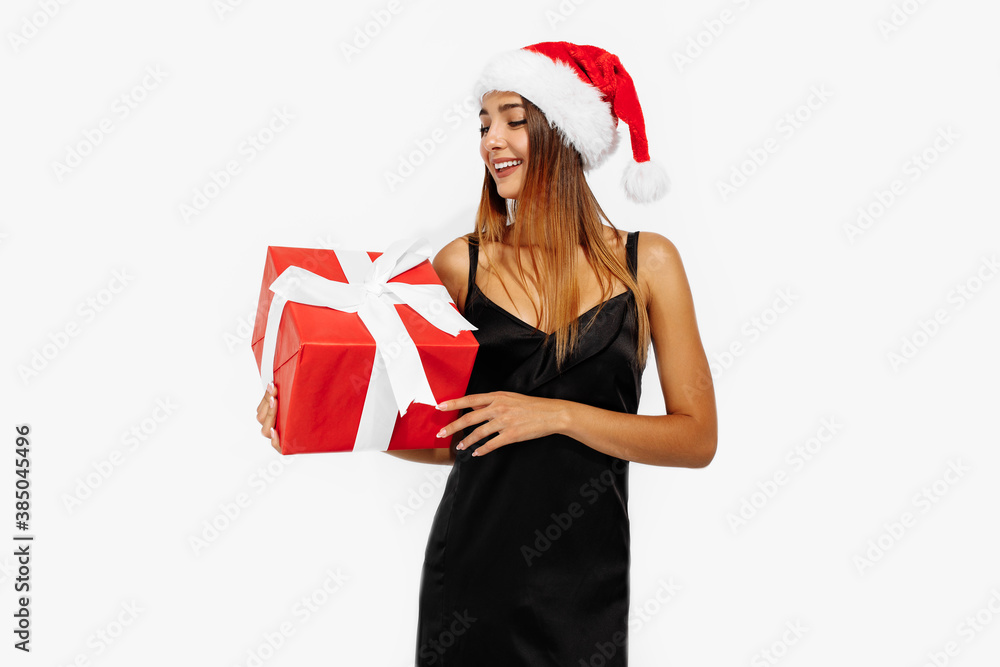 Happy beautiful young woman in santa claus hat with gift box on white background Happy beautiful young woman in santa claus hat with gift box on white background