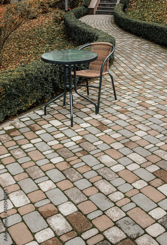 round table and chair on brick path in  autumn park without people