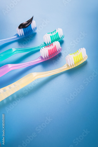 Set of four colorful toothbrushes with black charcoal paste