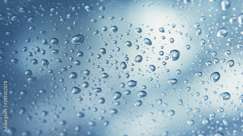 Real water drops on blue gradation background  close up. Raindrops on the window glass. Condensation