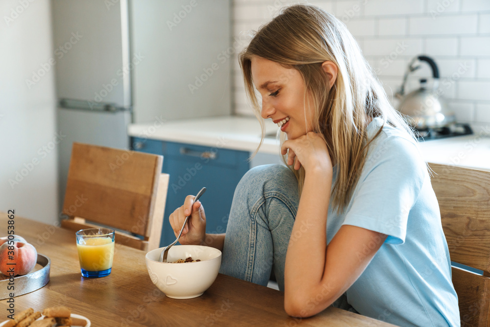 Beautiful joyful girl eating cereal while having breakfast