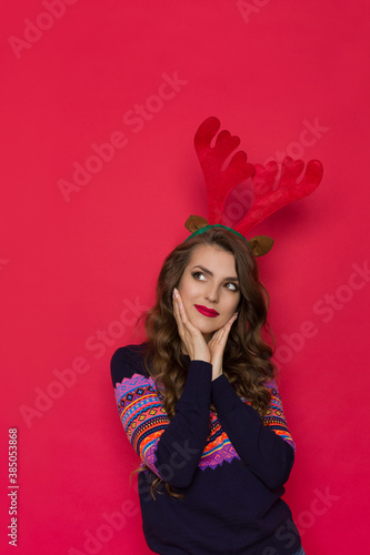 Beautiful Woman Wearing Christmas Reindeer Horns Holding Head In Hand And Dreaming