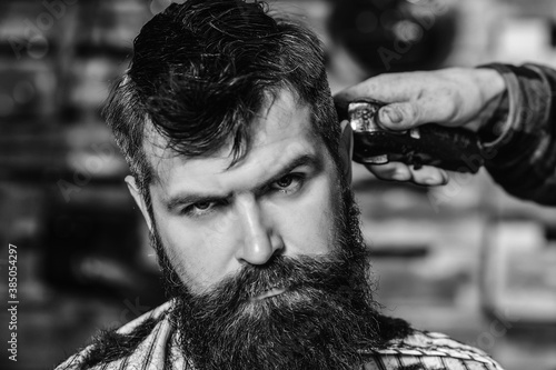 Hairstylist serving client. Barber making haircut using machine. Stylish bearded man in barber shop. New perfect style.