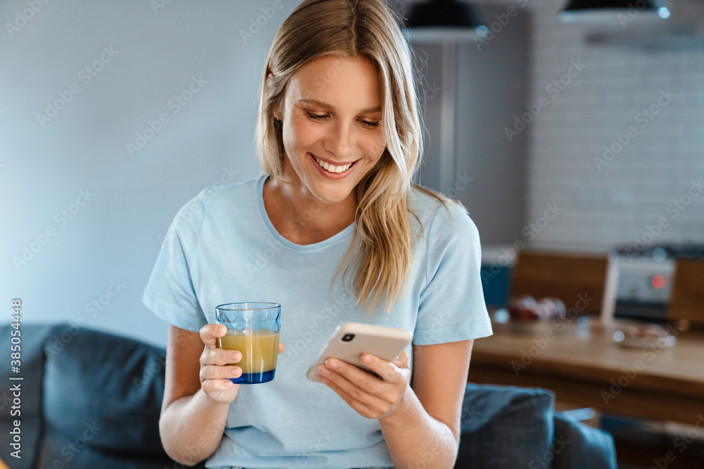 Beautiful joyful girl using cellphone and drinking juice Beautiful joyful girl using cellphone and drinking juice