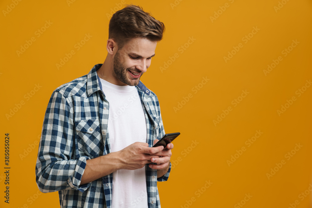Cheerful handsome guy smiling and using mobile phone Cheerful handsome guy smiling and using mobile phone