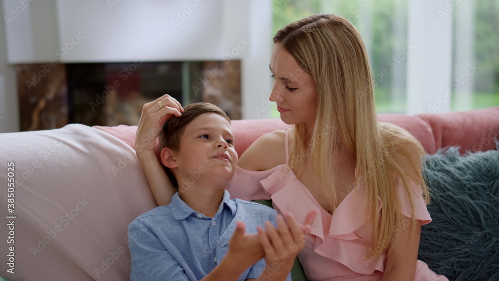 Mother and son talking together in living room. Careful woman touching boy hair Mother and son talking together in living room. Careful woman touching boy hair