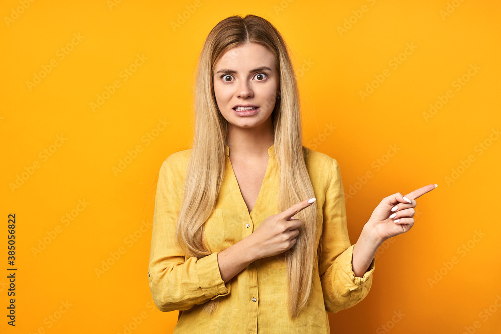 young woman in yellow shirt saluting with hand with happy facial expression over isolated yellow background. Friendly blonde smiling young woman in yellow shirt saluting with hand with happy facial expression over isolated yellow background. Friendly blonde smiling