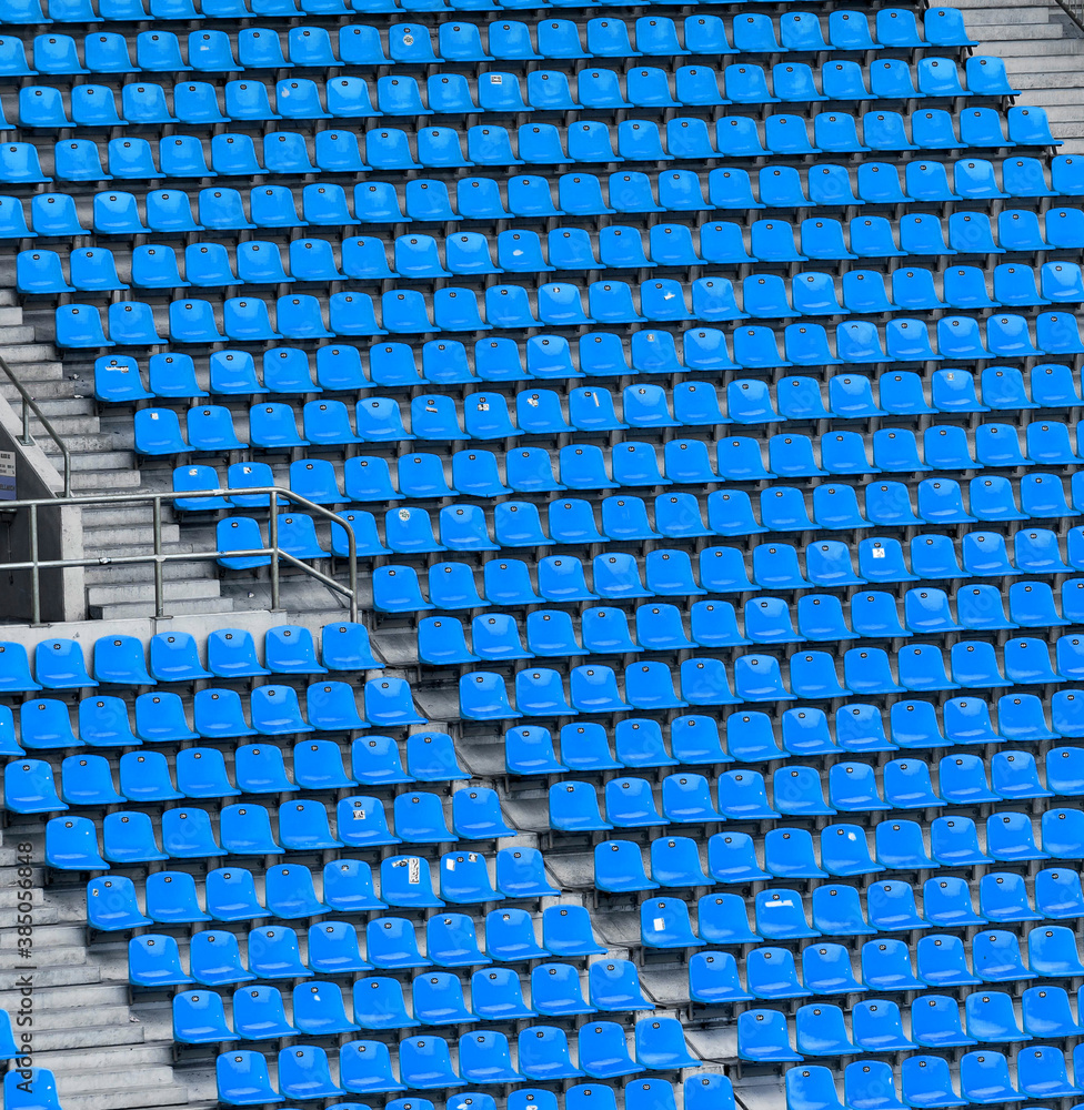 Naklejka premium Many rows of blue seats in a large sports stadium without spectators with concrete stairs.