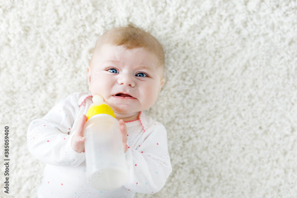 Cute adorable ewborn baby girl holding nursing bottle and drinking formula milk Cute adorable ewborn baby girl holding nursing bottle and drinking formula milk