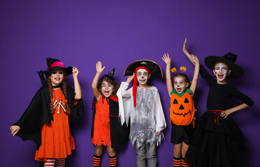 Cute little kids wearing Halloween costumes on purple background