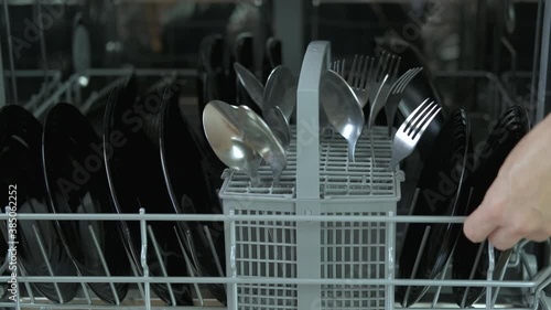 New dishwasher appliances. A woman puts glasses into a dishwash machine in the kitchen. A concept of modern appliences in the kitchen. photo