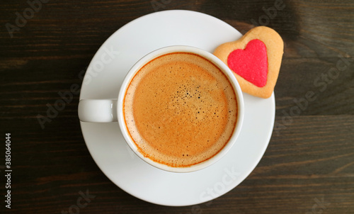 Top View of a Cup of Hot Coffee with Heart Shaped Cookie on Dark Brown Wooden Table for the Concept of LOVE