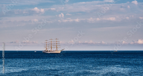 Beautiful three-masted sailboat over the background of the blue sea and cloudy sky. photo