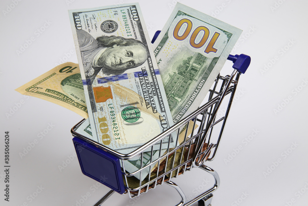 View on isolated shopping cart modell with us dollar paper bills, white blank background - purchase power and gross national domestic (gnp, gdp) product concept View on isolated shopping cart modell with us dollar paper bills, white blank background - purchase power and gross national domestic (gnp, gdp) product concept