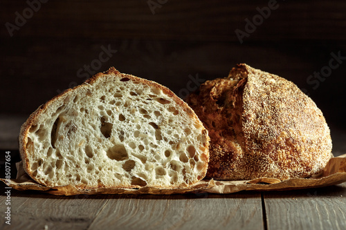 Foto Bread, traditional sourdough bread cut into slices on a rustic wooden background
