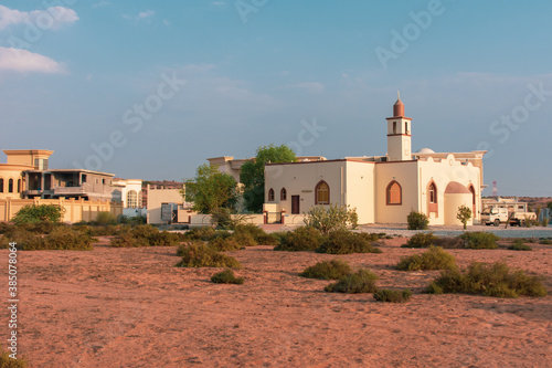 White Mosque in a residential area in the Middle East with a blue sky in the late afternoon sunshine. photo