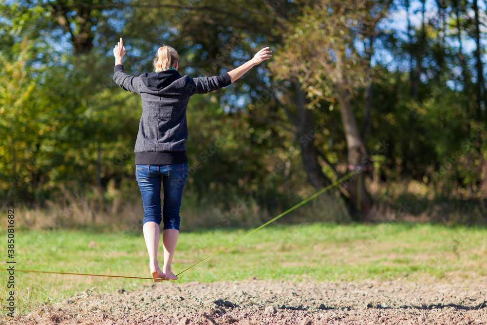 Woman balancing and jumping on slackline. Woman walking, jumping and balancing on rope in park