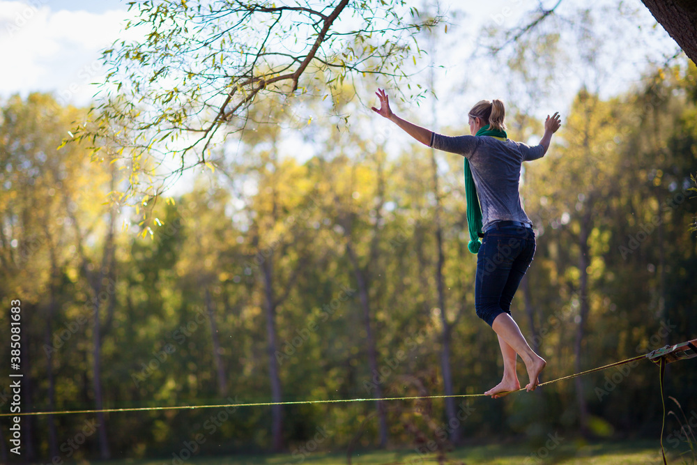 Woman balancing and jumping on slackline. Woman walking, jumping and  balancing on rope in park Sports a tightrope or slackline outdoor in a city  park in summer slacklining, balance, training concept Photos