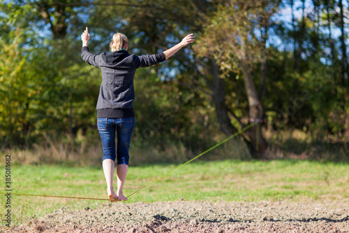 Woman balancing and jumping on slackline. Woman walking, jumping and balancing on rope in park Sports a tightrope or slackline outdoor in a city park in summer slacklining, balance, training concept