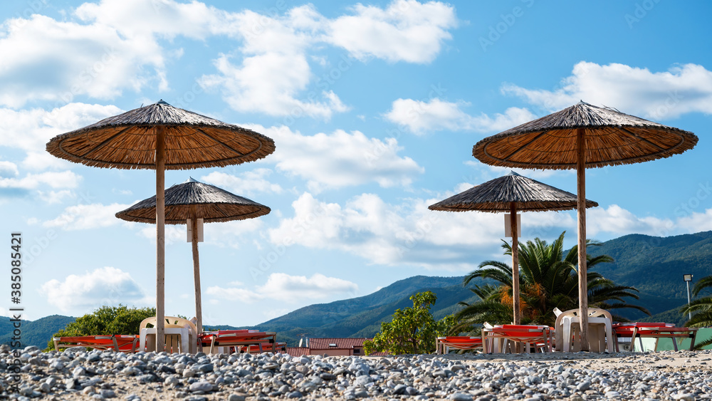 Log beach umbrellas with mountains on the background in Asprovalta