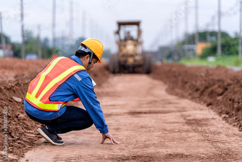 Civil engineer check the soil surface and control yellow vibratory soil and Motor Grader Civil compactor working in road construction site. photo