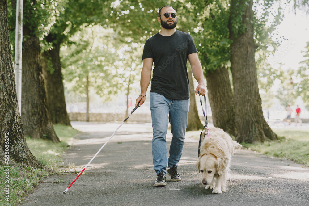 Guide dog helping blind man in the city. Handsome blind guy have rest with golden retriever in the city. Guide dog helping blind man in the city. Handsome blind guy have rest with golden retriever in the city.